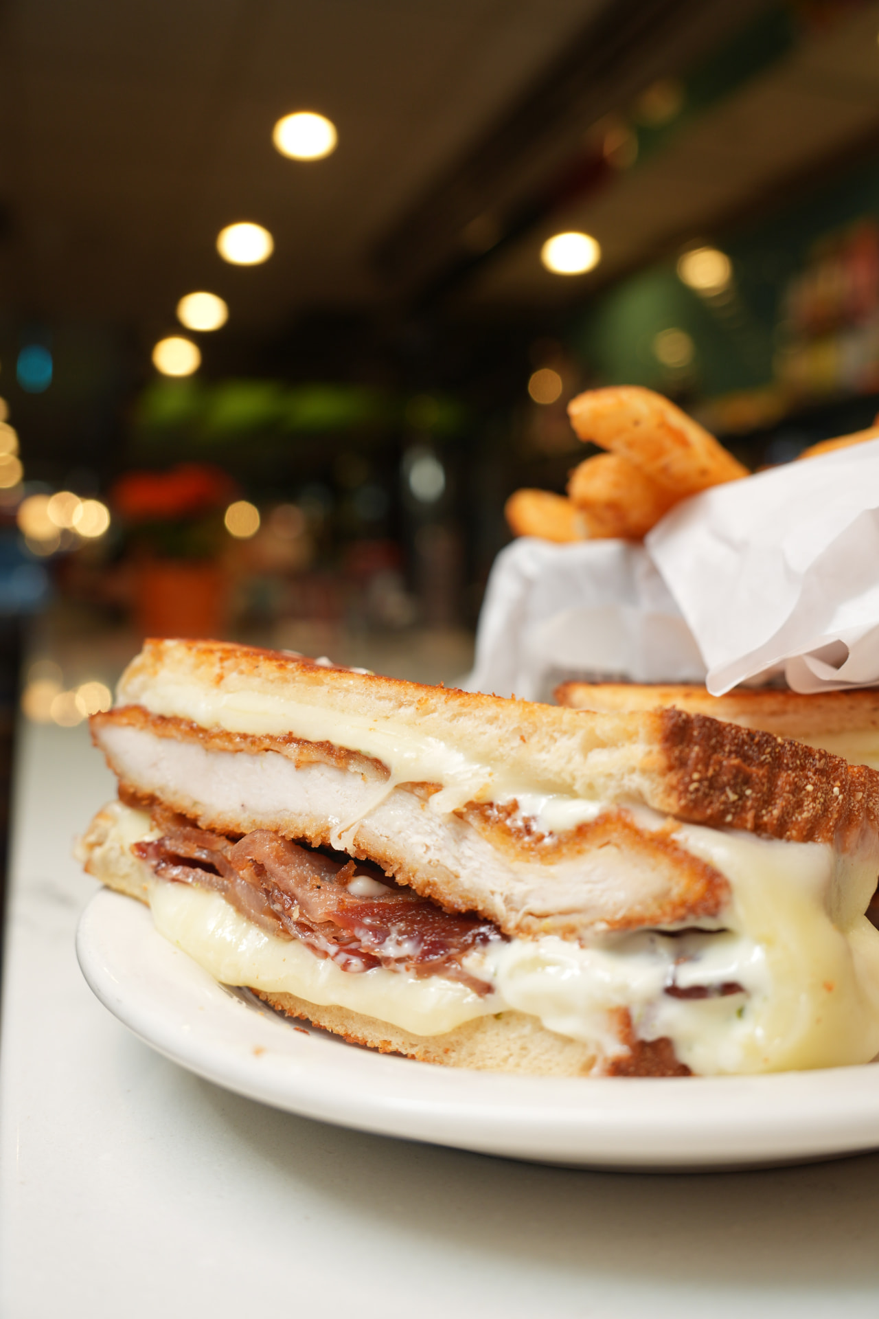 Chicken, bacon and melted cheese grilled sandwich with fries